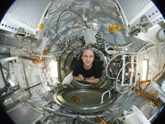 An older man floats inside a space vehicle.