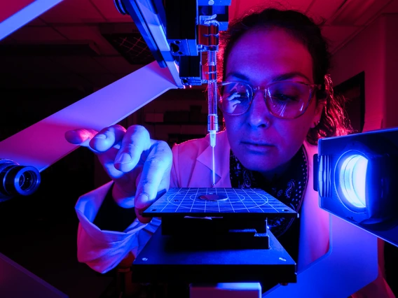 A woman looks at a microscope.