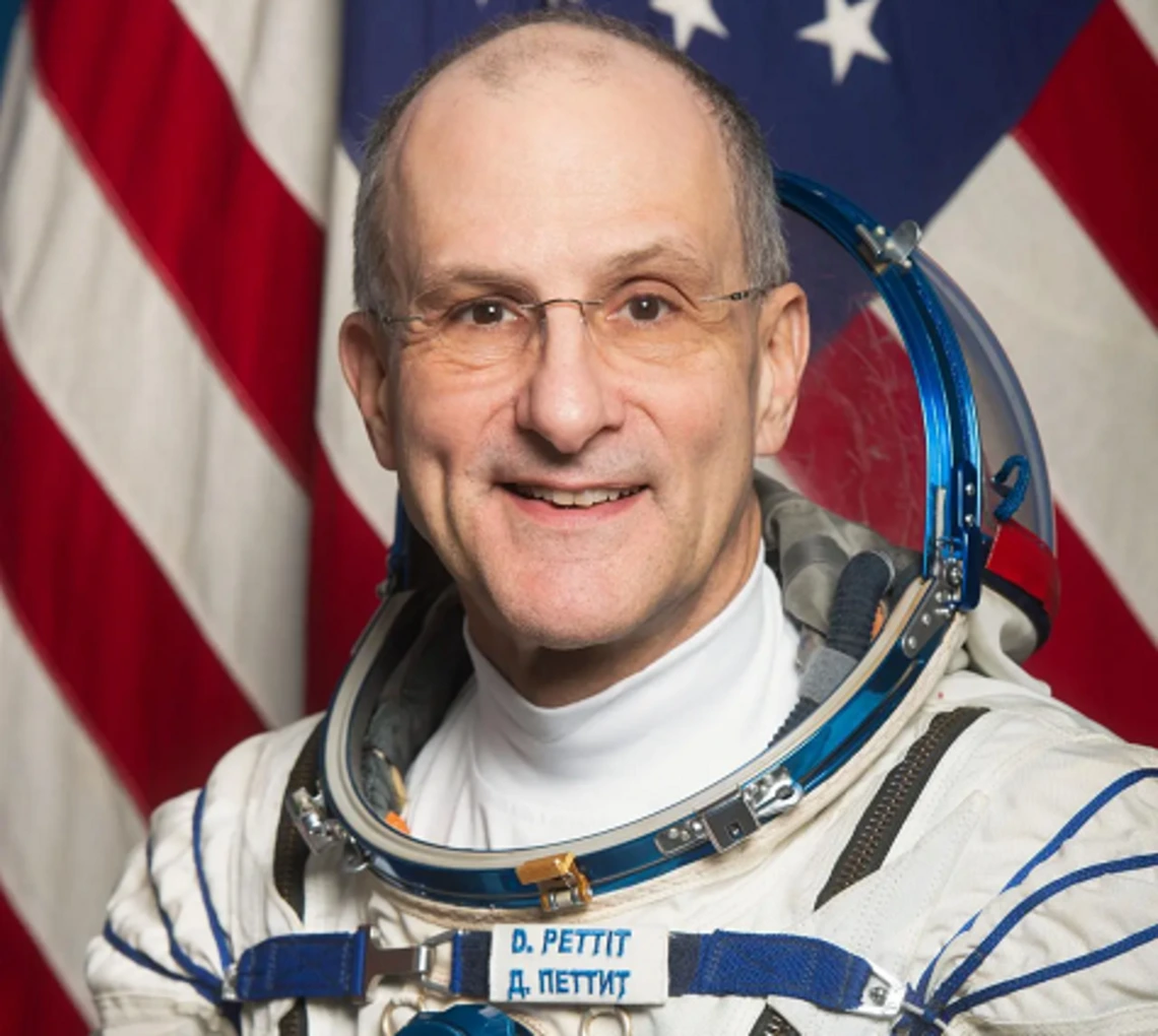 A headshot of Donald Pettit in his spacesuit in front of an American flag