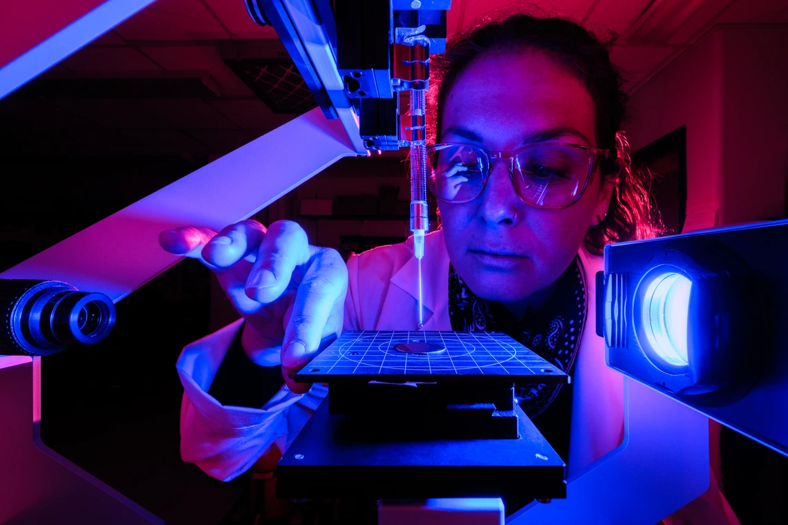A woman looks at a microscope.
