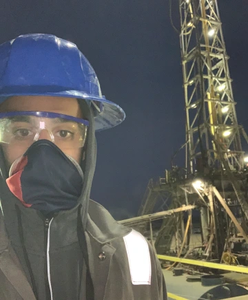 person wearing hard hat, goggles and mask at drilling site