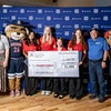 A mixed group of people hold a large check.
